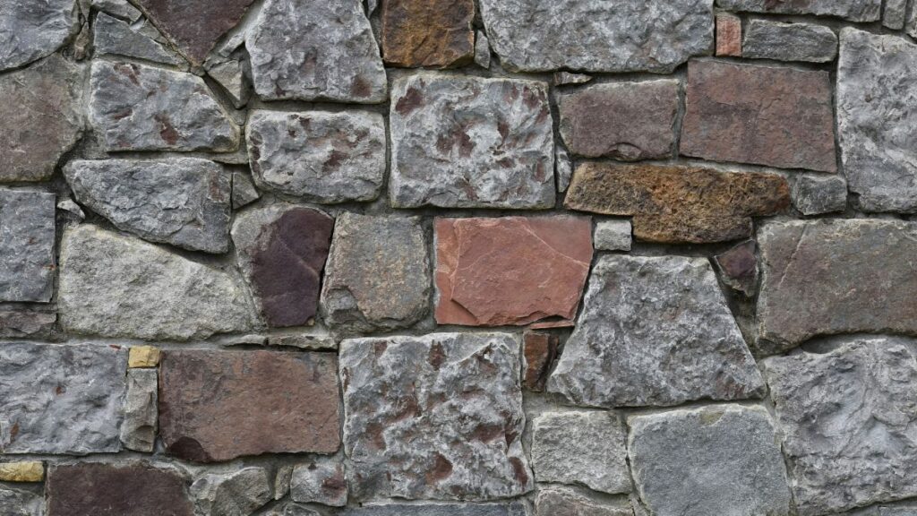 A close view of a weathered stone wall with visible seams and soft natural light, suggesting boundaries formed gradually over time.