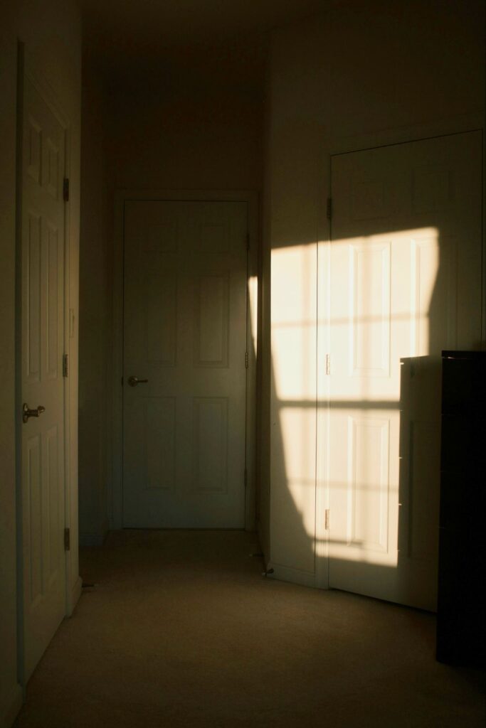 Sunlight falls across closed doors in a quiet, empty hallway